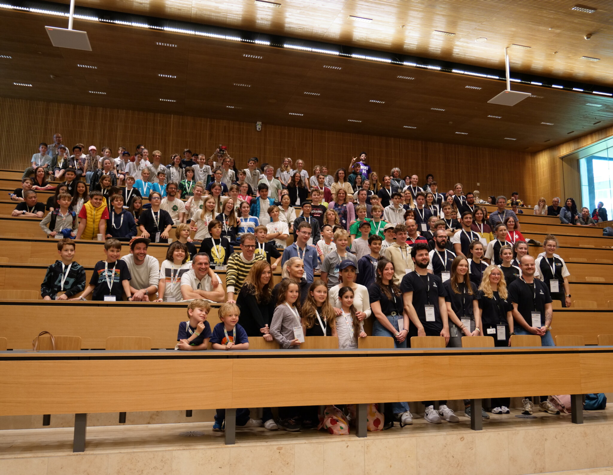 Tim Schmid steht inmitten der Teilnehmenden der World Robotic Olympiad 2024