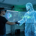 Ein Mensch reicht einer digitalen Jesusfigur die Hand.