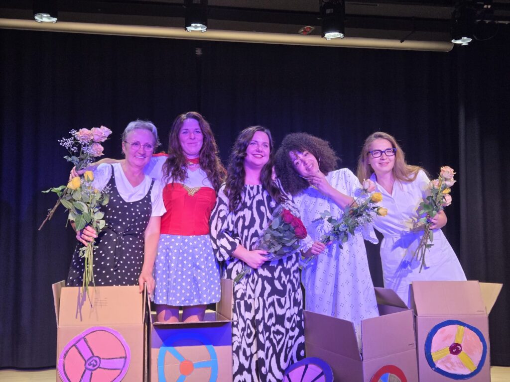 5 Laiendarstellerinnen auf einer Theaterbühne, rechts auch Aygul 