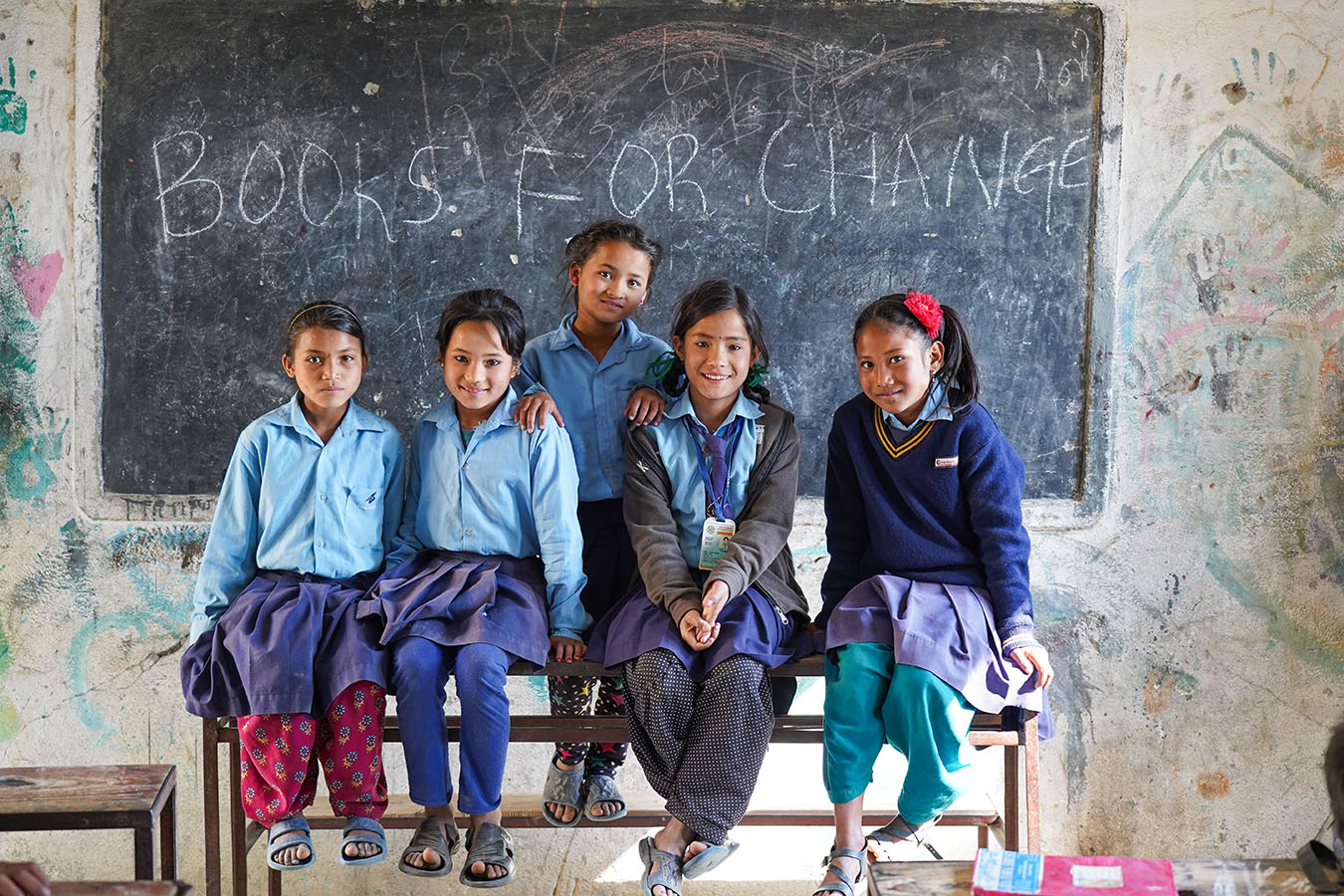 Schulkinder vor einer BOOKS FOR CHANGE Wandtafel