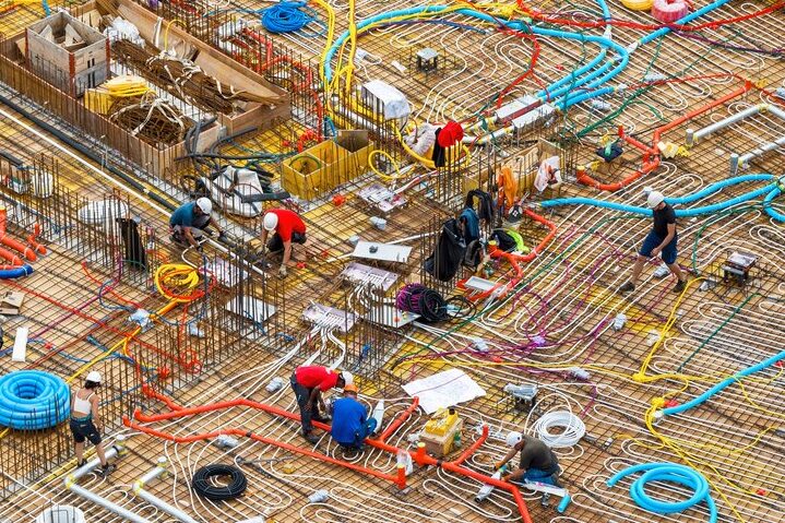 Bauarbeiter verlegen Leitungen im Rohbau eines Wohngebäudes.