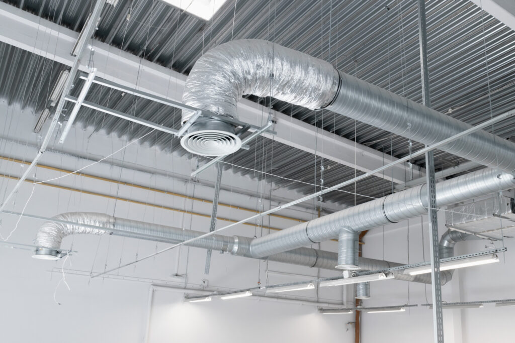 Ventilation and air conditioning system on the ceiling of an industrial building, metal ventilation pipes